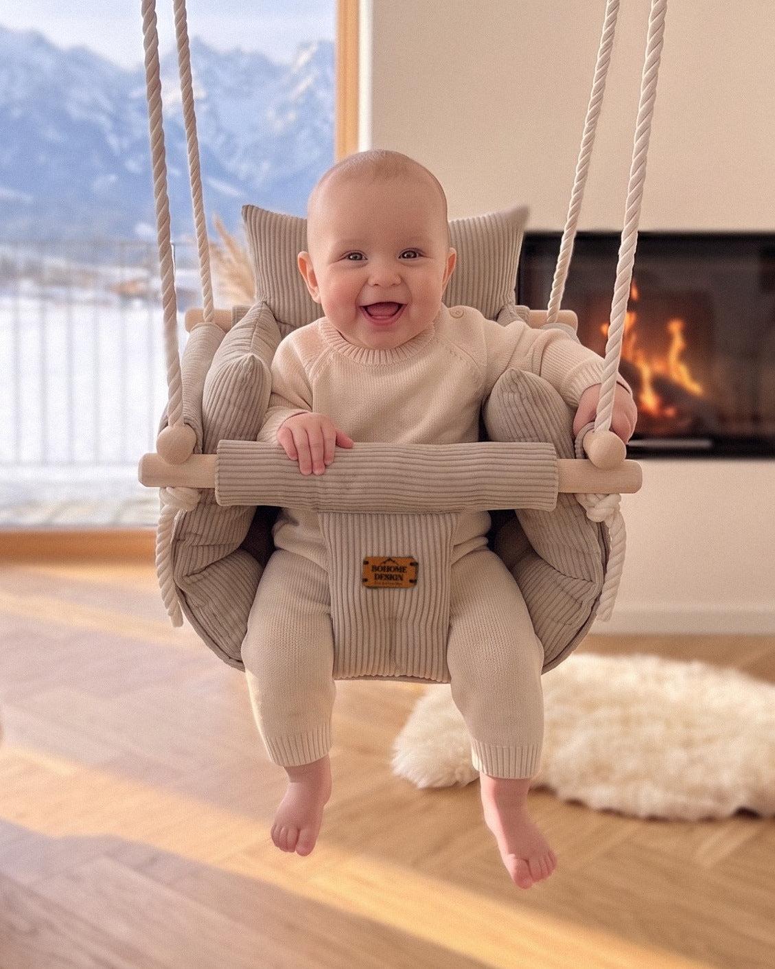 BOHOME Premium Babyschaukel Nougat Latte – fröhliches Baby in der handgefertigten Schaukel im Wohnzimmer mit Alpenblick