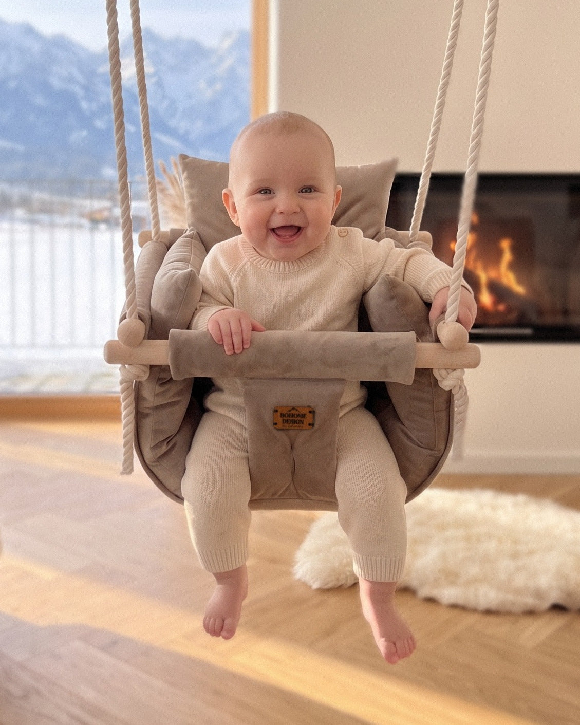 BOHOME Premium Babyschaukel Sand Beige – fröhliches Baby in der handgefertigten Schaukel im Wohnzimmer mit Alpenblick